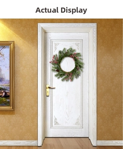 Close-up of Christmas wreath with red berries, pine needles and cones on a white door