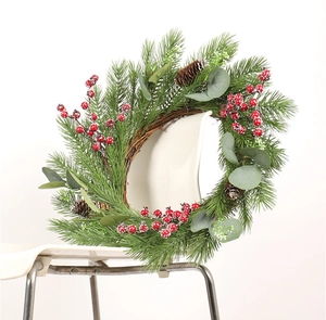 Detail of Christmas wreath with red berries, pine cones and eucalyptus on rattan