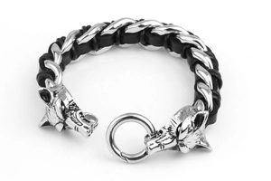 Detailed view of dual wolf head steel charms on a black braided leather bracelet for men