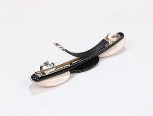 Detail view of pink and black oval acetate hair clip with metal fastener