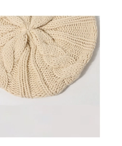 Macro detail of cream cable knit texture and pattern on a children's wool beret hat