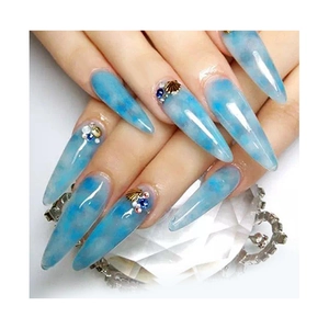 Long stiletto press-on nails with blue marble pattern, gold shells, and rhinestones