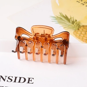Close-up of amber brown translucent hair claw clip with interlocking teeth and metal spring