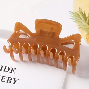 Macro shot of large glossy brown plastic hair claw clip with multi-tooth design detail