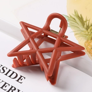 Macro shot of matte brick red star-shaped hair claw clip with cutout geometric details