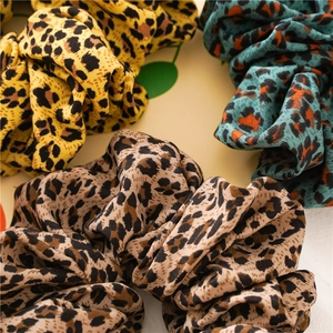 Close-up of leopard print hair scrunchies in yellow, teal, and brown chiffon fabric