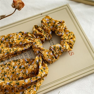 Macro shot of yellow floral hair scrunchie with ribbons on a book background
