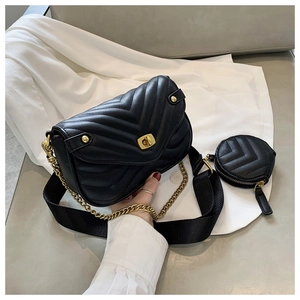 Detail of black V-quilted faux leather bag with gold chain and mini round pouch accessory