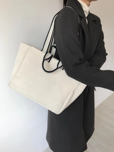Detail of minimalist canvas tote bag in cream white with navy blue handles and straps