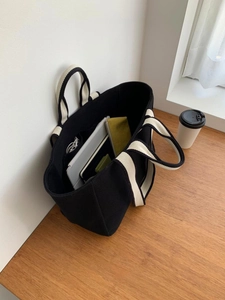 Spacious black canvas tote bag showing interior storage for laptop and tablet
