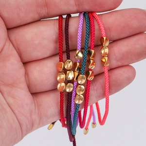 Detail of colorful woven bracelets with irregular golden beads and fiber texture