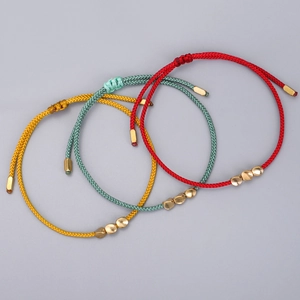 Close-up of woven rope bracelets with irregular golden beads in red yellow and blue