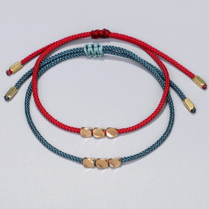 Detail of red and dark cyan hand-woven bracelets with adjustable golden metal accents