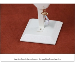 Detailed shot of golden bow earring with rainbow crystals on a white leather jewelry stand
