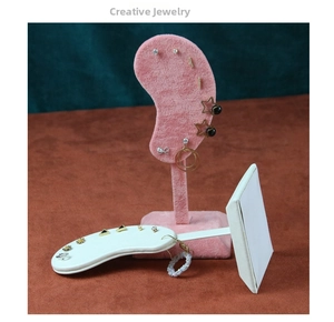 Pink velvet ear-shaped display stand and white leather bar holder with various earrings