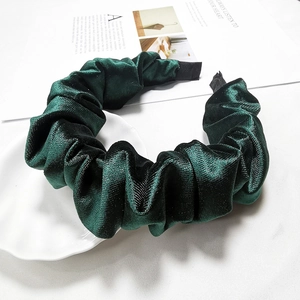 Close-up of a dark green pleated velvet headband on a decorative shell plate