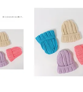 Détail de bonnets en grosse maille bleue, beige et lavande avec revers pliés