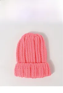 Détail du bonnet en maille rose vif montrant la texture épaisse et le bord replié