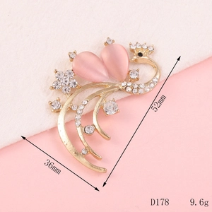 Detailed view of a golden peacock brooch with pink crystal and white rhinestones