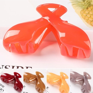 Macro detail of large glossy claw clip showing various colors like burgundy and yellow