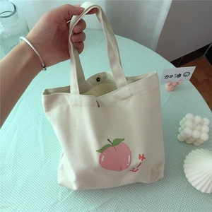 Kleine cremefarbene Segeltuchtasche mit süßem Pfirsichdruck in Lifestyle-Szene