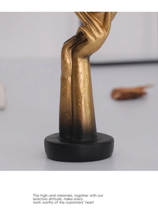 Close-up of golden abstract mask sculpture with grainy texture on a black pedestal