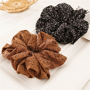 Detail of brown and black polka dot fabric scrunchies on a white minimalist frame