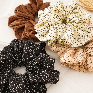 Close-up of four oversized polka dot fabric scrunchies in brown beige and black tones