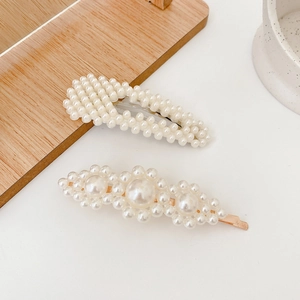 Elegant set of pearl hair clips with golden base on minimalist light wooden tray