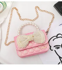 Detail of pink glitter mini bag featuring a large pearl bow and elegant pearl handle