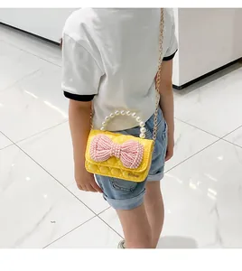 Detail of yellow quilted mini bag with pink pearl bow and gold chain strap for girls