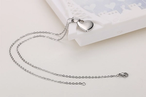 Detailed view of silver heart pendant necklace with O-chain on white surface