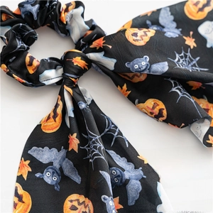 Detail of Halloween satin hair scrunchie featuring pumpkin, bat and spider web patterns
