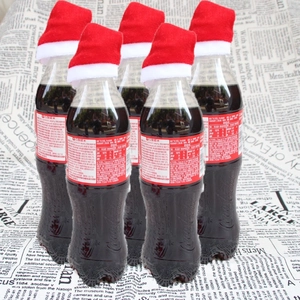 Makroaufnahme kleiner rot-weißer Weihnachtsmützen auf Flaschenverschlüssen als Deko