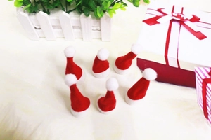 Detailansicht von sechs roten Mini-Weihnachtsmützen aus Filz auf flauschigem Hintergrund