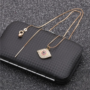 Golden Evil Eye necklace with red gemstone and white zircons on black textured box