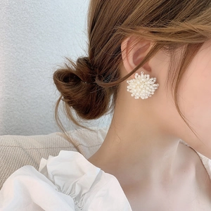 Detailansicht eleganter weißer Perlenohrringe in Blumenform, getragen von einem Model