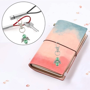 Detail of angel wing ornament with green beads and silver wings on a notebook
