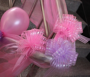 Pink and purple organza pull bows decorating a metal staircase railing for a wedding