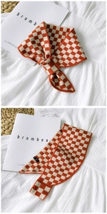 Detailed knit texture of orange and beige checkerboard scarf on a white fabric background