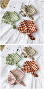 Close-up of checkered knit scarves in green, khaki, orange and pink color options