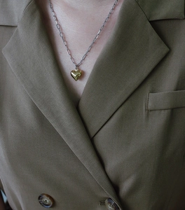 Close-up of a two-tone paperclip chain necklace with a 3D gold heart pendant on a blazer