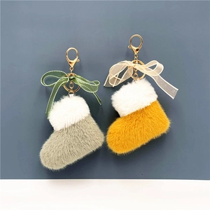 Detailed plush Christmas boot keychains in light green and yellow with ribbon bows