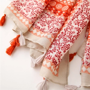 Detailed view of bohemian floral cotton scarf with tassel trim in orange and beige tones