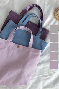 Detail of colorful canvas tote bags with metal snap buttons and fine twill texture