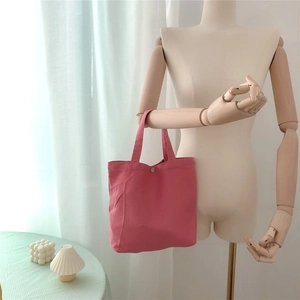 Detailed view of pink canvas tote bag with snap button closure on a mannequin arm