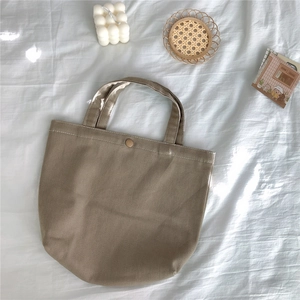 Macro detail of khaki corduroy tote bag showing vertical texture and metal snap closure