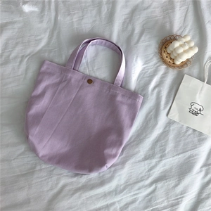 Detail of purple corduroy canvas tote bag with a brown button closure on fabric background