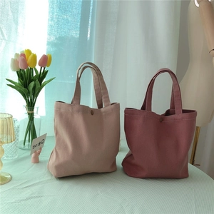 Detail of canvas tote bags showing textured twill fabric and secure magnetic clasp