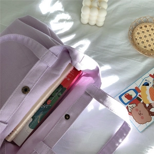 Detailed texture of lavender corduroy tote bag with magnetic snap button and books